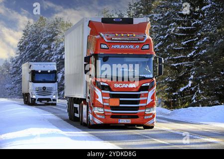 Due autocarri per il trasporto merci trasportano merci sull'autostrada invernale 52, Scania R500 Haukala rossa e FNA rimorchio nella parte anteriore. Salo, Finlandia. 11 febbraio 2021 Foto Stock