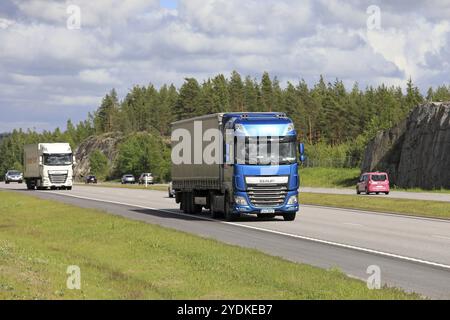 PAIMIO, FINLANDIA, 25 GIUGNO 2017: I semirimorchi DAF XF blu e bianchi trasportano merci lungo l'autostrada tra il traffico in una splendida giornata d'estate Foto Stock