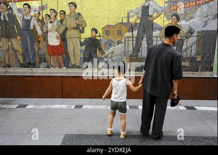 09.08.2012, Pyongyang, Corea del Nord, Asia, Un padre aspetta con suo figlio sulla piattaforma di una stazione della metropolitana a Pyongyang. In background, si può Foto Stock