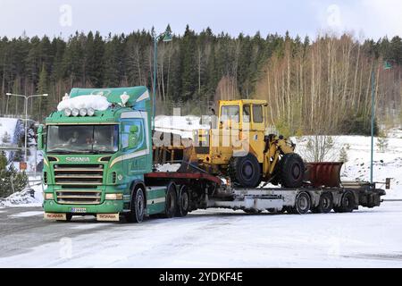 Salo, Finlandia, 9 marzo 2019: Veicolo Scania verde con rimorchio con caricatore ribassato Noteboom per il trasporto di una vecchia pala gommata pronta per il trasporto in una giornata invernale, UE Foto Stock