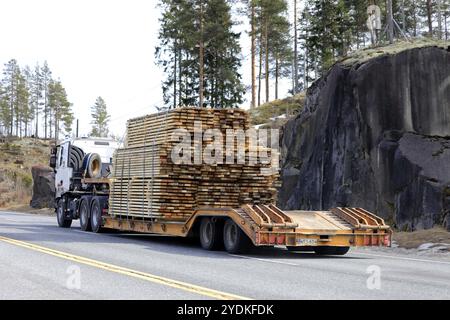 Salo, Finlandia, 19 aprile 2019: Il camion tira un carico pesante di legname su un rimorchio a collo d'oca lungo l'autostrada in un giorno di primavera, vista posteriore, Europa Foto Stock