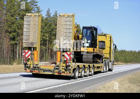 Vista posteriore dell'escavatore idraulico Cat 315FL, trasporto su strada con rimorchio a collo d'oca Volvo FH 500 Truck in una giornata limpida di primavera a Raasepori, Finlandia, Apri Foto Stock