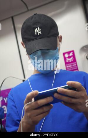 28.02.2020, Singapore, Repubblica di Singapore, Asia, Un giovane uomo indossa una maschera in un treno sotterraneo per proteggersi dall'infezione del pandem Foto Stock