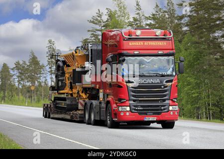 Il camion Red Scania R580 trasporta il tritarifiuti Tana Shark 440DT su un rimorchio con pianale ribassato come carico largo lungo la strada 25. Raasepori, Finlandia. 27 maggio 2021 Foto Stock