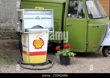 Vecchio distributore di benzina Shell di Avery-Hardoll su un cortile con veicolo Piaggio Ape verde a tre ruote. Riihikoski, Finlandia. 11 giugno 2022 Foto Stock