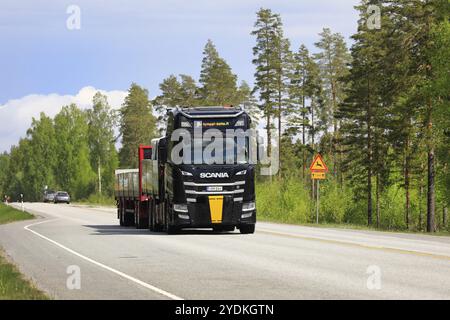 Il camion nero Scania e il rimorchio aperto di Kymppi-Katto Oy trasporta il carico su strada 25 in una giornata di sole. Raasepori, Finlandia. 26 maggio 2022 Foto Stock