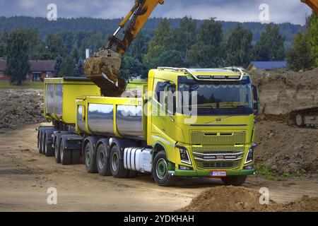 Escavatore cingolato che carica il terreno su un rimorchio a cassette Volvo FH16 verde. Salo, Finlandia. 27 agosto 2022 Foto Stock