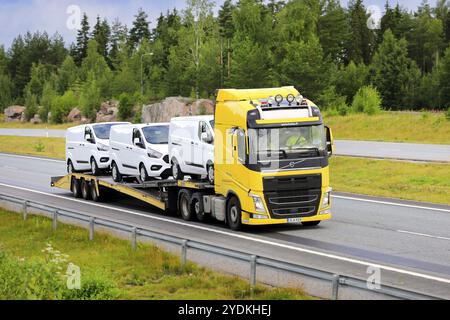 Il camion Volvo FH 540 giallo trasporta tre furgoni Ford bianchi in autostrada in un giorno d'estate. Salo, Finlandia. 29 luglio 2022 Foto Stock