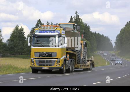 SALO, FINLANDIA, 30 LUGLIO 2016: Il semi giallo Volvo FH16 di Mantyla e&e trasporta la pala gommata Caterpillar 980H su un rimorchio con pianale ribassato su un'autostrada rurale a. Foto Stock