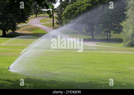 Sprinkler nel parco che innaffiano l'erba in una calda giornata d'estate in Finlandia Foto Stock