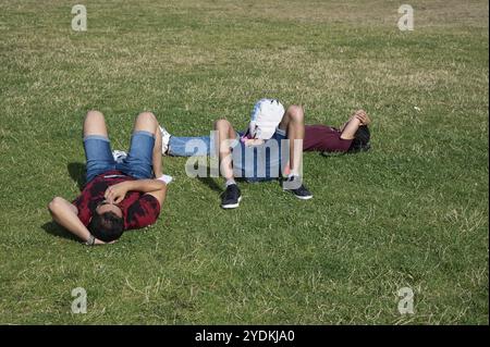 23.07.2022, Berlino, Germania, Europa, tre uomini si trovano sul prato di fronte al Reichstag nel quartiere Mitte di Berlino e godono di una giornata estiva di sole, UE Foto Stock