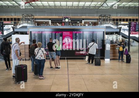 04.06.2023, Berlino, Germania, Europa, una foto interna mostra i viaggiatori aerei di fronte a una bacheca con partenze al Terminal 1 di Berlin-Brande Foto Stock