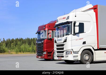 I veicoli con semirimorchio Scania S580 rossi e Scania R500 bianchi sono parcheggiati in un'area di sosta in una giornata di sole d'estate. Jalasjarvi, Finlandia. 10 agosto 2019 Foto Stock