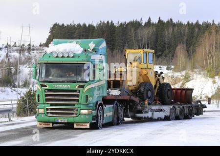 Salo, Finlandia, 9 marzo 2019: Veicolo Scania verde con rimorchio con caricatore ribassato Noteboom per il trasporto di una vecchia pala gommata pronta per il trasporto in una giornata invernale, UE Foto Stock