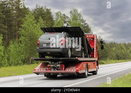 Veicolo di recupero con pianale Renault di Ostermans Alltrans Ab Oy che trasporta auto danneggiata lungo l'autostrada in giornata nuvolosa. Raasepori, Finlandia. 24 maggio 2019 Foto Stock