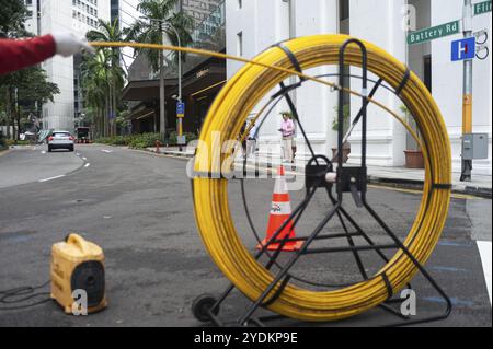 15.04.2018, Singapore, Repubblica di Singapore, Asia, Un lavoratore posa cavi su una strada nel quartiere degli affari, Asia Foto Stock