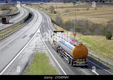 Il carro armato procede sulla rampa autostradale e fa attenzione al segnale di snervamento prima di entrare in strada in un giorno limpido di primavera Foto Stock