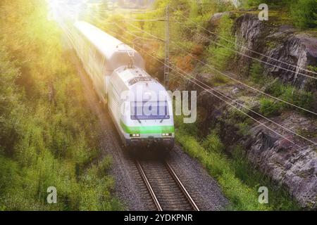 Il treno VR Intercity viaggia a velocità sostenuta attraverso il paesaggio rurale con alberi verdi e una vista elevata. Salo, Finlandia. 29 agosto 2021 Foto Stock