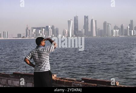 13.09.2010, Doha, Qatar, Un uomo guarda dalla passeggiata lungo al Corniche Street allo skyline del quartiere degli affari di al Dafna all'ingresso Foto Stock