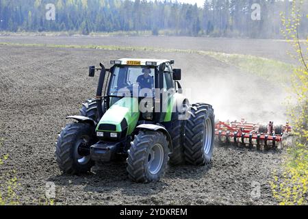 Campo coltivatore con trattore verde Deutz-Fahr Agrotron 135 e erstad NZ con erpice a denti aggressivo in primavera. Salo, Finlandia. 13 maggio 2021 Foto Stock