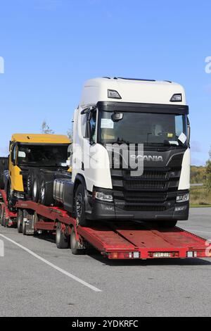 Supporto per veicoli che trasporta due nuovi carrelli Scania, bianco R650 e giallo R650 XT, parcheggiato nel deposito di sosta per camion. Vista verticale. Salo, Finlandia. 5 ottobre 201 Foto Stock