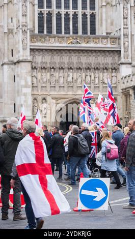 I manifestanti di "Unisci il Regno" con le bandiere inglesi e britanniche marciano pacificamente oltre l'Abbazia di Westminster, Londra, Inghilterra, il 26 ottobre 2024. Foto Stock