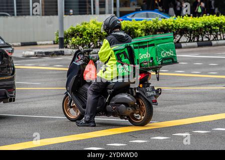 Una persona singaporiana che utilizza il cellulare su uno scooter si fermò ad un incrocio nel traffico di Singapore Foto Stock