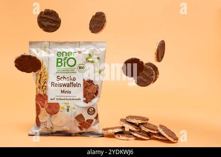 Germania Berlino 26 ottobre 2024. Un pacchetto di cialde di cioccolato ENER Bio, da cui le cialde di cioccolato volano su sfondo arancione. Eccitazione e p Foto Stock