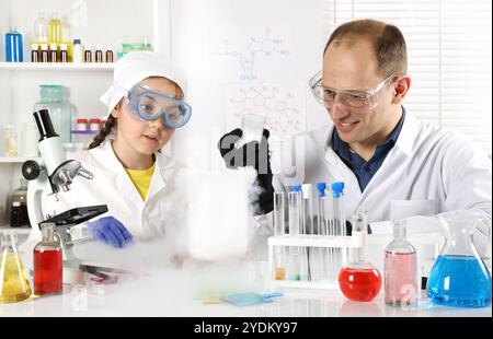 Un giovane scienziato conduce lezioni di chimica per una bambina facendo esperimenti con azoto liquido e ghiaccio secco in un laboratorio chimico Foto Stock