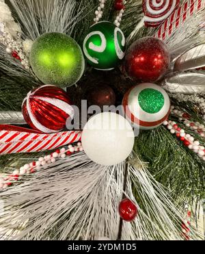 Primo piano della corona di Natale decorata con baule natalizie verdi rosse e bianche Foto Stock