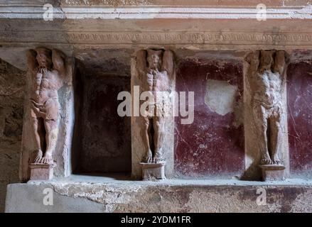 Statue in miniatura decorano le pareti all'interno di una casa termale di Pompei, parco archeologico di Pompei, Napoli Italia. Foto Stock