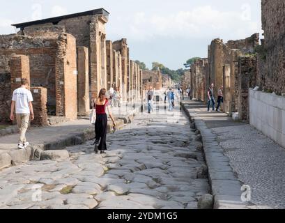 Strada lastricata di pietra che mostra solchi di carri e carri, Parco Archeologico di Pompei, Napoli, Italia. Foto Stock