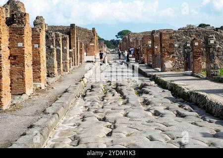 Strada lastricata di pietra che mostra solchi di carri e carri, Parco Archeologico di Pompei, Napoli, Italia. Foto Stock