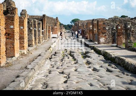 Strada lastricata di pietra che mostra solchi di carri e carri, Parco Archeologico di Pompei, Napoli, Italia. Foto Stock