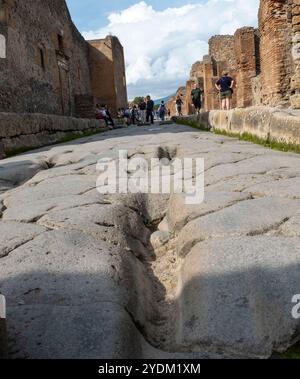 Strada lastricata di pietra che mostra solchi di carri e carri, Parco Archeologico di Pompei, Napoli, Italia. Foto Stock