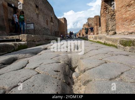 Strada lastricata di pietra che mostra solchi di carri e carri, Parco Archeologico di Pompei, Napoli, Italia. Foto Stock