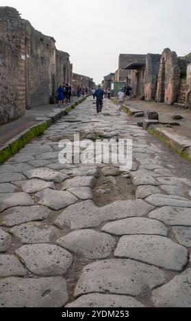 Strada lastricata di pietra che mostra solchi di carri e carri, Parco Archeologico di Pompei, Napoli, Italia. Foto Stock