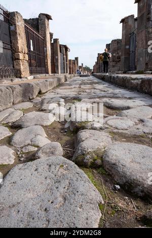 Strada lastricata di pietra che mostra solchi di carri e carri, Parco Archeologico di Pompei, Napoli, Italia. Foto Stock