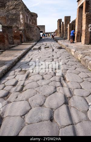 Strada lastricata di pietra che mostra solchi di carri e carri, Parco Archeologico di Pompei, Napoli, Italia. Foto Stock