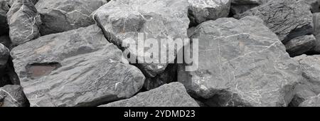 Rinforzo costiero con grandi rocce di granito in riva al mare Foto Stock