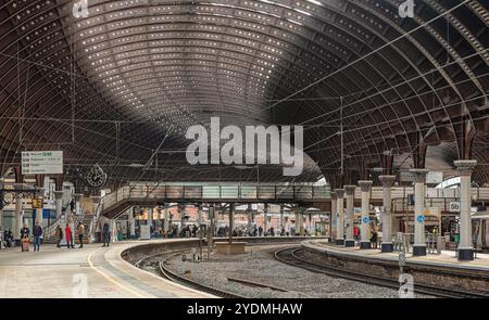 Una piattaforma della stazione ferroviaria, fiancheggiata da colonne, curve, in un atrio principale. Una storica tettoia del XIX secolo è sopra la testa e i passeggeri sono sulla plat Foto Stock