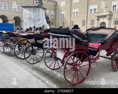 Salisburgo, Austria - 1° ottobre 2024: Carrozze trainate da cavalli tradizionali parcheggiate nel centro storico di Salisburgo in attesa di un giro panoramico Foto Stock