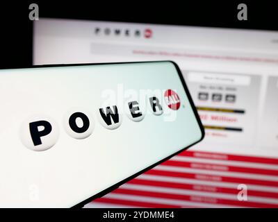 Cellulare con logo del gioco della lotteria statunitense Powerball sullo schermo davanti al sito Web. Mettere a fuoco la parte centrale sinistra del display del telefono. Foto Stock