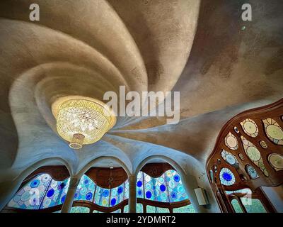 Barcellona, Spagna. 27 ottobre 2024. Fantastici lampadari e vetrate colorate impreziosiscono gli interni di Casa Batla'". Casa Batll'" è un edificio nel centro di Barcellona, in Spagna, progettato da Antoni Gaud', ed è considerato uno dei suoi capolavori. Come tutto ciò che Gaud' ha progettato, Casa Batlll'" è identificabile solo come Modernisme nel senso più ampio. Il piano terra presenta finestre ovali irregolari e lavori in pietra scolpita. Ci sono poche linee rette, e gran parte del faÂade è decorato con un mosaico colorato fatto di piastrelle di ceramica rotte. Il tetto è arcuato ed è stato paragonato al retro di Foto Stock