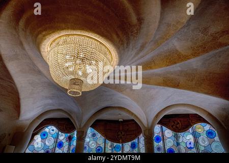 Barcellona, Spagna. 27 ottobre 2024. Fantastici lampadari e vetrate colorate impreziosiscono gli interni di Casa Batla'". Casa Batll'" è un edificio nel centro di Barcellona, in Spagna, progettato da Antoni Gaud', ed è considerato uno dei suoi capolavori. Come tutto ciò che Gaud' ha progettato, Casa Batlll'" è identificabile solo come Modernisme nel senso più ampio. Il piano terra presenta finestre ovali irregolari e lavori in pietra scolpita. Ci sono poche linee rette, e gran parte del faÂade è decorato con un mosaico colorato fatto di piastrelle di ceramica rotte. Il tetto è arcuato ed è stato paragonato al retro di Foto Stock