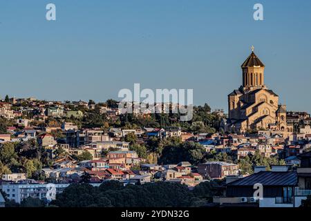 Tbilisi, Georgia. 27 ottobre 2024. Soleggiato e sereno, il paesaggio di Tbilisi cattura un momento tranquillo attraverso il fiume domenica 27 ottobre 2024, dopo le elezioni. L'imponente cattedrale di Sameba sorge sopra i tetti della città, con la sua cupola dorata che risplende di una tranquilla maestosità. Dalle tradizionali case in collina all'architettura urbana, lo skyline di Tbilisi riflette un'armoniosa miscela di vecchio e nuovo. (VX Photo/ Vudi Xhymshiti) crediti: VX Pictures/Alamy Live News Foto Stock