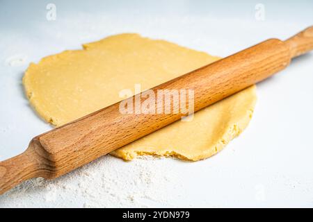 Impasto a forma di cerchio arrotolato per pizza o torta su un tavolo leggero con un mattarello di legno. Foto di alta qualità Foto Stock