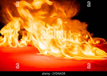Un tavolo da biliardo è inondato di fiamme, con palline scintillanti sparse sul feltro rosso carbonizzato. Il fumo si arriccia verso l'alto, generando ombre inquietanti Foto Stock