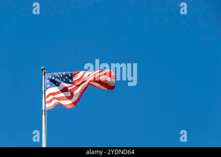 Le stelle e le strisce americane sventolano contro un cielo azzurro, simboleggiando la libertà e il patriottismo negli Stati Uniti Foto Stock