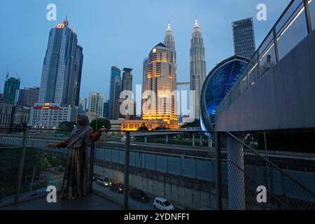 Kuala Lumpur, Malesia - 29 luglio 2023: Donna musulmana in posa per una foto di fronte al ponte di Saloma e alle iconiche Petronas Towers, situate nel KLCC. Foto Stock